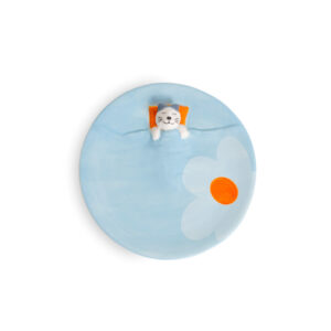 The Blue Dreamer Cat - Jewellery Plate is a round blue plate with a painted white flower and orange centre, plus a small 3D cat figure lounging with an orange pillow&mdash;showcasing curated Estonian design and originality. Gate21.ee