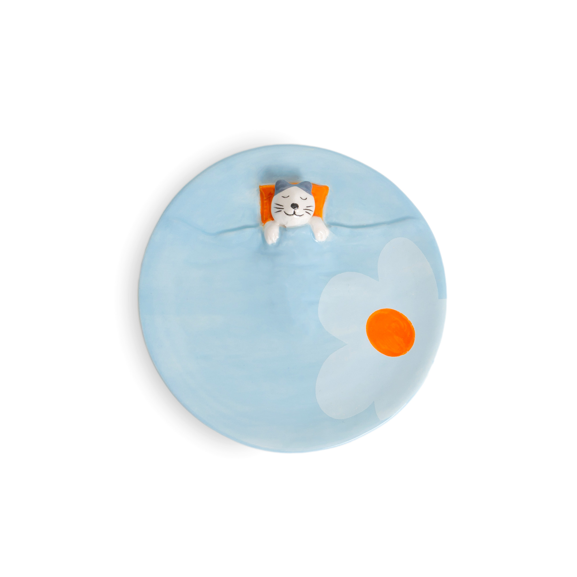 The Blue Dreamer Cat - Jewellery Plate is a round blue plate with a painted white flower and orange centre, plus a small 3D cat figure lounging with an orange pillow—showcasing curated Estonian design and originality. Gate21.ee