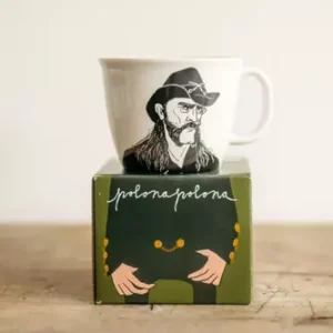 The hoarse-voiced Cowboy - Large cup is a white mug with an illustrated man sporting long hair, a moustache, and cowboy hat. Packaged in an Estonian-designed box with a green jacket, gold buttons, and "polona polona" handwriting. Gate21.ee