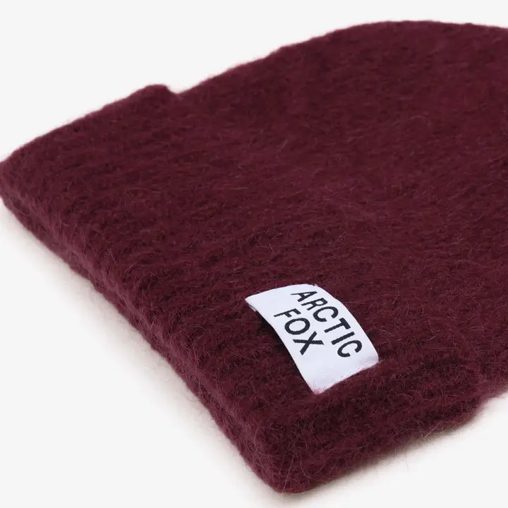 The Mohair Beanie - Cherry Burgundy from Arctic Fox, a maroon knitted beanie with a visible ARCTIC FOX fabric tag in black lettering, showcased on a white background. Gate21.ee