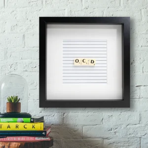 The OCD - Scrabble Print features the letters “O, C, D” on lined paper in a black square frame. Perfect for display above books or plants, it’s a unique piece sure to evoke memories or spark conversation. Gate21.ee