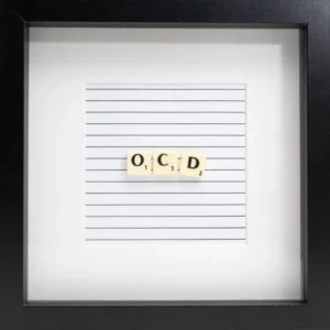 The OCD - Scrabble Print features Scrabble tiles spelling "OCD" on lined paper, framed with a white mount and black border—perfect for sparking memories or marking special occasions. Gate21.ee