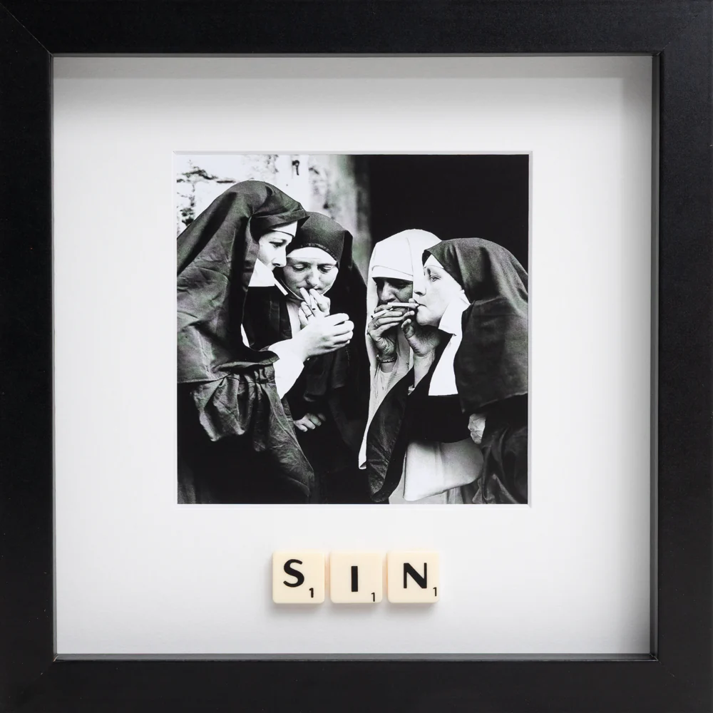 The SIN - Scrabble Print features a black-and-white photo of four women dressed as nuns, smoking together. "SIN" is spelt out in Scrabble tiles below the image—all in a black frame, perfect for sparking memories or conversation. Gate21.ee