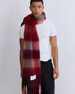A person stands against a plain background, wearing a fitted white t-shirt, black trousers, and The Reykjavik Scarf - Burgundy Check wrapped around the neck and draped down the front. Gate21.ee