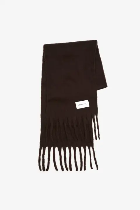 The Reykjavik Scarf - Ground Coffee is a dark brown scarf with long fringe at both ends and a rectangular white label sewn on one side, shown against a plain white background. Gate21.ee