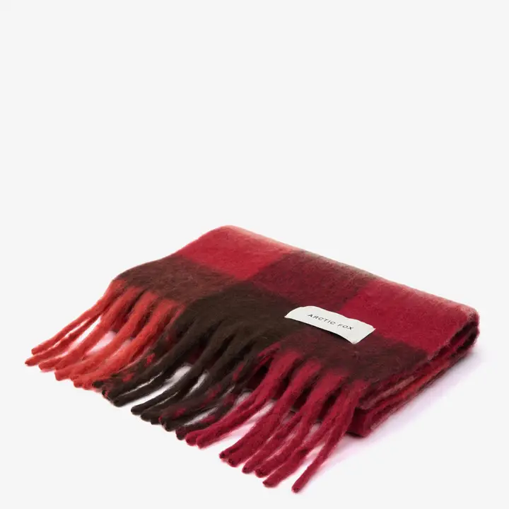 The Reykjavik Scarf - Burgundy Check is a folded, rectangular scarf with a red and dark brown check design, fringed ends, and an Arctic Fox label. It is displayed on a plain white background. Gate21.ee