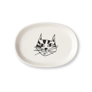 The Kitty - Tray is an oval-shaped white ceramic dish by Helen B, featuring a minimalist black line drawing of a cat’s face in the centre against a plain black background. Gate21.ee