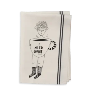 The Couple Tea Towel - Need Coffee features a folded white towel with two black stripes and an illustration of a curly-haired person in striped socks holding a large coffee cup labelled "I NEED COFFEE (now). Gate21.ee