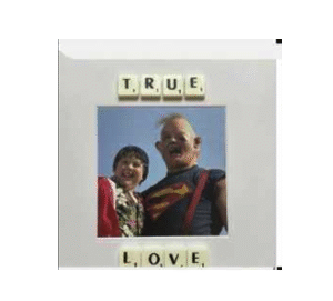 A child and an adult in a superhero shirt smile beneath Scrabble tiles spelling TRUE and LOVE. The TRUE LOVE - Scrabble Print is perfect for sparking memories or celebrating moments that matter!. Gate21.ee
