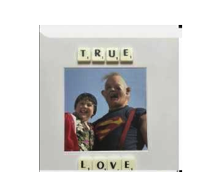 A child and an adult in a superhero shirt smile beneath Scrabble tiles spelling TRUE and LOVE. The TRUE LOVE - Scrabble Print is perfect for sparking memories or celebrating moments that matter!. Gate21.ee