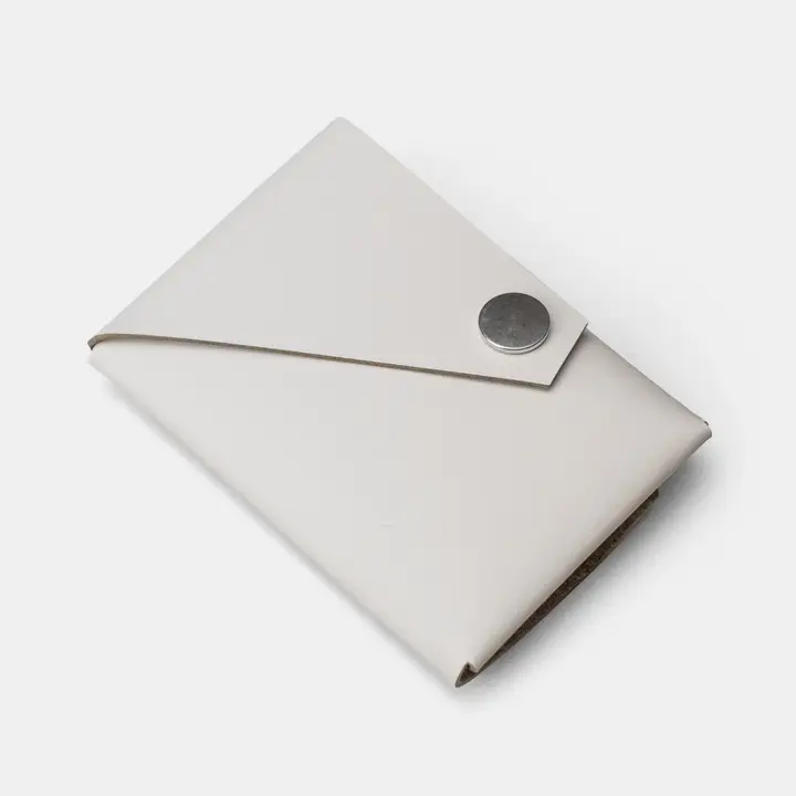 The LEMUR - White Wallet is a minimalist envelope-style wallet with a silver circular press stud, shown against a plain light grey background. Gate21.ee