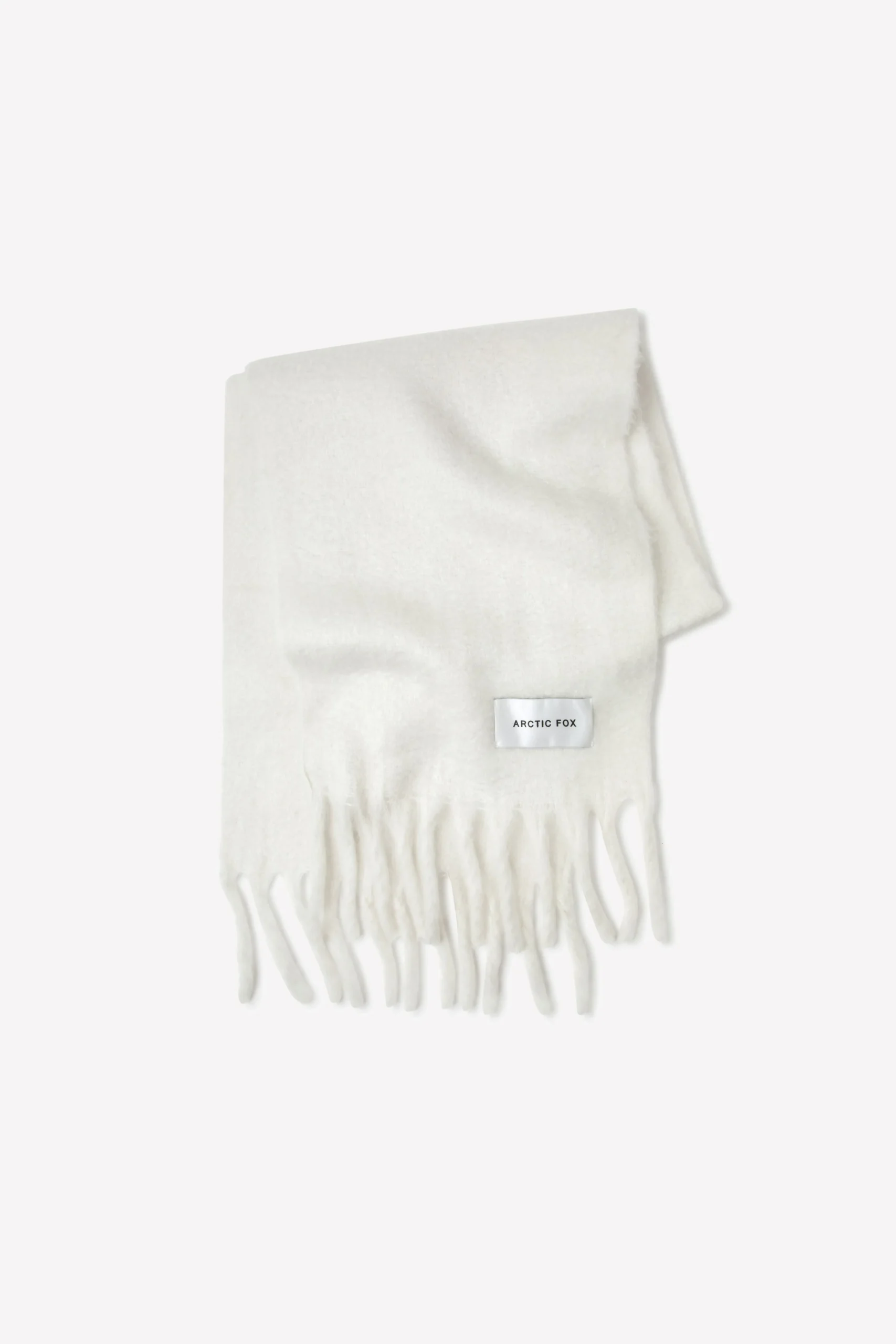 The Stockholm Scarf - Polar White is a folded white scarf with fringed ends and a small rectangular ARCTIC FOX STOCKHOLM label, displayed on a plain white background. Gate21.ee
