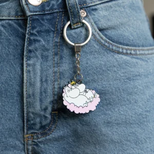 The Moomin Keyring - Love Buddies adds charm as it hangs from the belt loop of blue jeans, featuring a white creature with a yellow crown and pink cloud. Gate21.ee