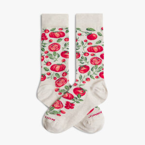 A pair of Tomato Fever - Beige socks by Jimmy Lion, cream-coloured with a red tomato and green leaf pattern, featuring partially visible red text on the toes. The socks are laid flat side by side. Gate21.ee