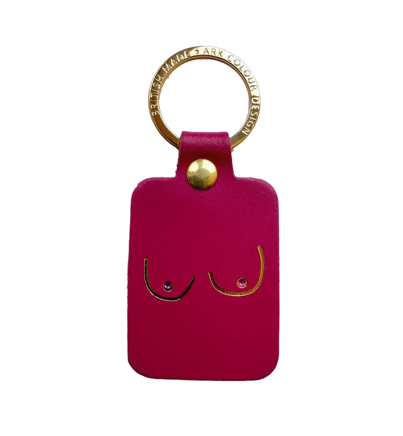 The Boob Key Ring - Magenta is a rectangular pink leather keyring with a gold metal ring and stud. It features a minimalist line drawing of breasts, accented with small crystals as nipples for a playful, chic look. Gate21.ee