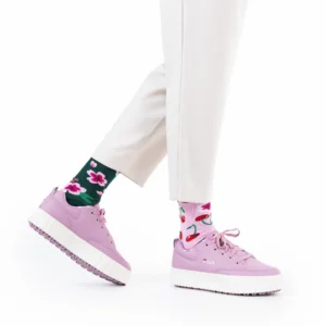 A person wearing white trousers, Cherry Blossom floral-patterned socks, and light purple Fila platform trainers stands against a white background. Only their lower legs and feet are visible. Gate21.ee