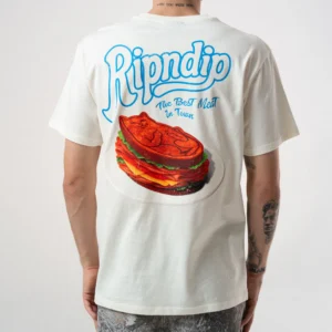 A person is seen from the back wearing the Best Meat Tee - Bone, featuring Ripndip's 'The Best Meat in Town' and a steak sandwich with a cat face, echoing the playful RIPnDIP style. Gate21.ee