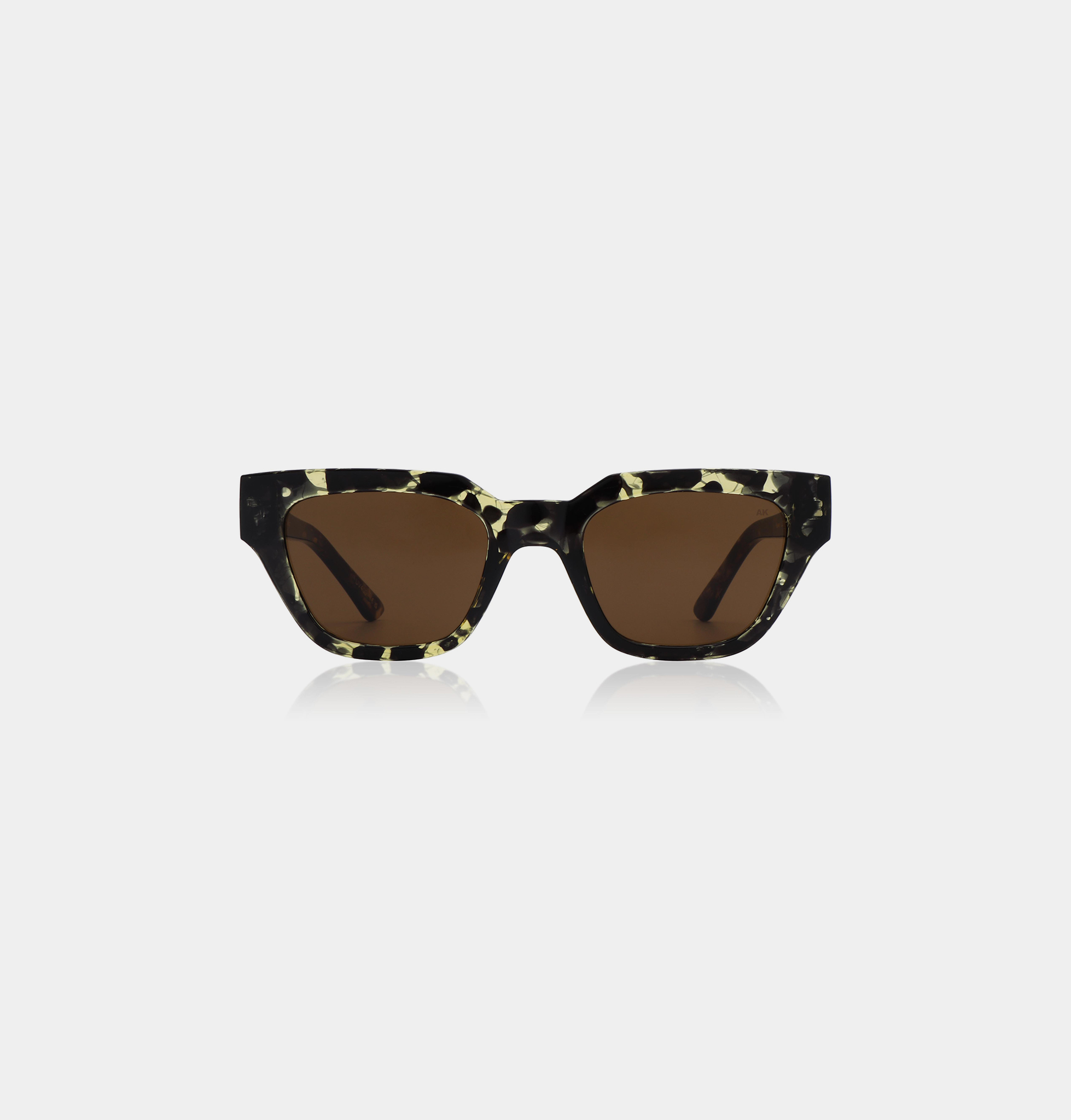 A pair of KAWS - Black/Yellow Tortoise A. Kjærbede sunglasses with square-shaped frames in a black-and-yellow tortoiseshell pattern and dark brown lenses, displayed against a plain white background. Gate21.ee