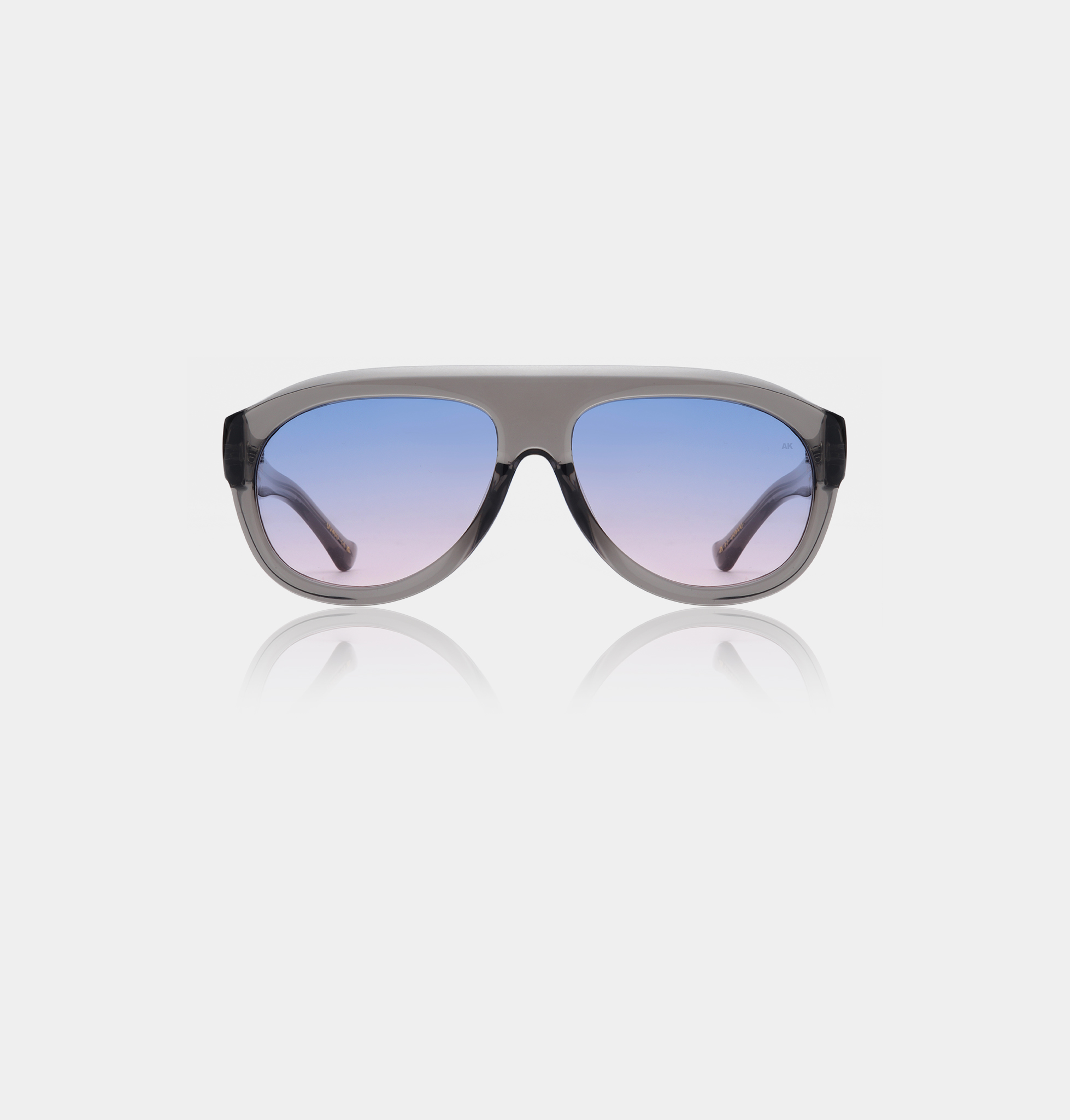 The Rio - Grey transparent sunglasses by A. Kjærbede feature a thick, translucent grey frame and large gradient lenses fading from blue to pink, shown against a white background. Gate21.ee