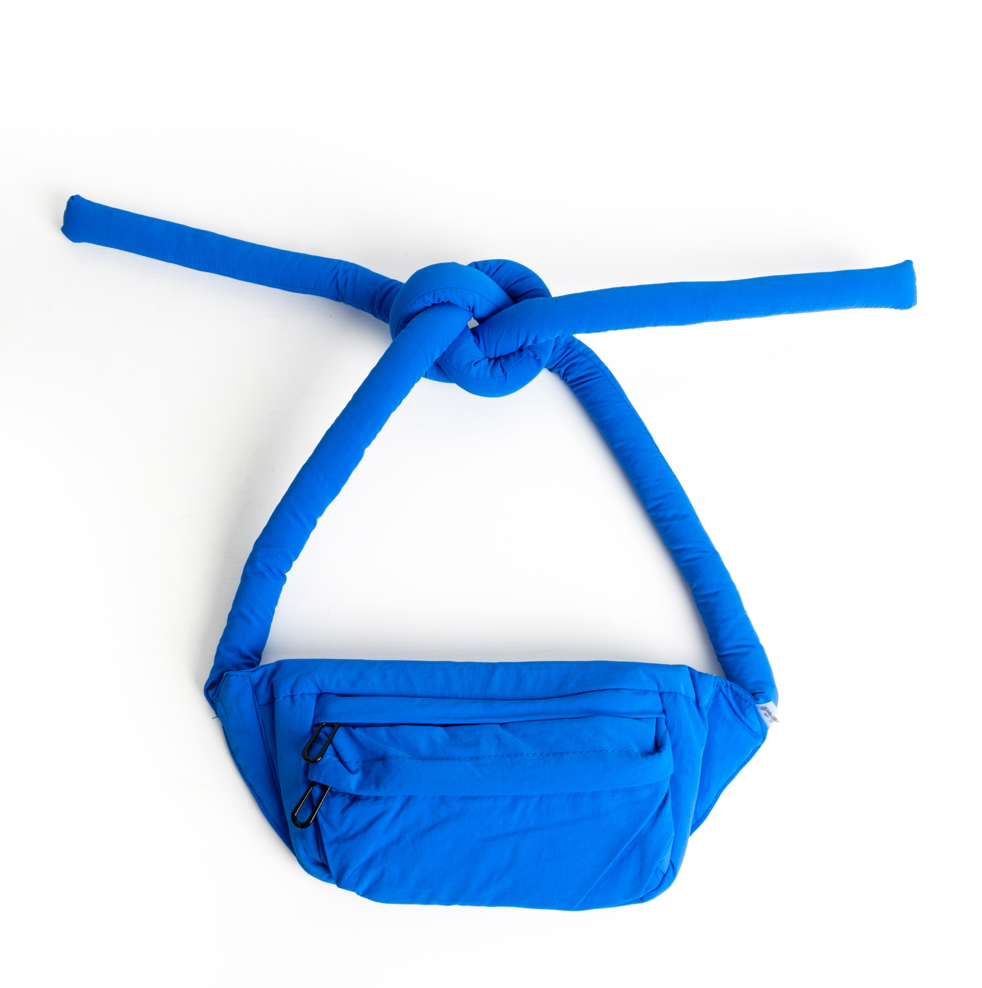 A magenta fabric bag called the Knotflex Pack, featuring a large, Knotflex-padded knotted strap, is shown against a white background. The bag has a front zip pocket and showcases a simple, modern design. Gate21.ee
