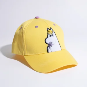 The Snorkmaiden Kids Cap is a yellow baseball cap with purple accents, featuring an embroidered Snorkmaiden character holding a flower on the front, echoing the playful style of Moomin merchandise. The cap is displayed on a white surface, casting a soft shadow to its left. Gate21.ee