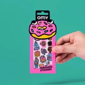 A hand holds a pink package labelled “Donut - Fabulous Stickers”, featuring colourful cartoon stickers of doughnuts, cupcakes, ice cream, and other desserts. The packaging showcases a large doughnut illustration at the top and includes playful OMY sticker earrings among the sweet-themed designs. Gate21.ee