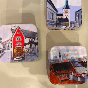 Old Town Coasters - Olevuse Art - KÕIK: Set of three square coasters featuring charming illustrated cityscapes—a red house, a church with a tall spire, and rooftops against a skyline—arranged on a light-coloured surface. Gate21.ee