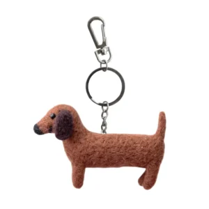Introducing the “Sausage Dog - Felt key ring”: a charming accessory crafted from soft felt in the playful shape of a brown dachshund, complete with a round black nose, black eyes, and dark brown ears. This delightful keyring features a sturdy metal ring and a silver carabiner clip for effortless attachment to your keys or bag. Gate21.ee