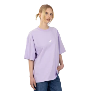 A person with fair hair styled in a low ponytail wears the loose-fitting Lavender Moomin Heavy T-shirt, which features a small white graphic on the chest, paired with blue jeans against a plain white background. Gate21.ee