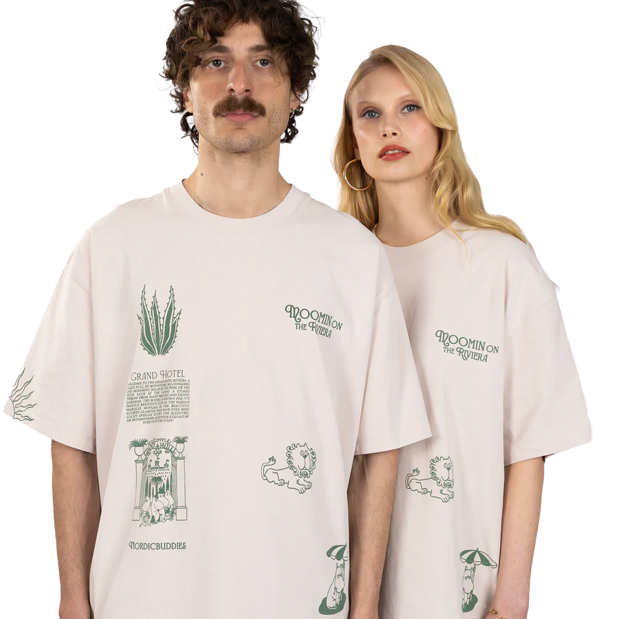 A man and a woman stand side by side wearing oversized white “Moomin Heavy Ts - Riviera” T-shirts, which feature green Moomin-themed graphics and text. Both look straight ahead with neutral expressions against a plain white background. Gate21.ee