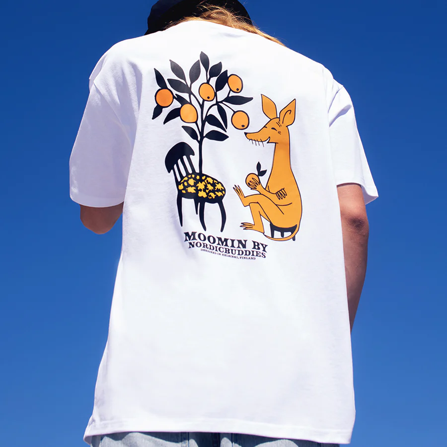 Person wearing a white “Moomin Ts - Sniff - White” T-shirt featuring a graphic of Sniff (the yellow creature), a chair with flowers, and a fruit tree against a blue sky. The shirt reads MOOMIN BY NORDEGBUDDIES. Gate21.ee