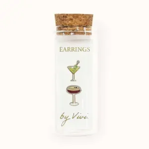 A clear glass vial with a cork lid holds the Champagne earrings by Vivi, featuring delightful designs shaped like a martini and a cocktail glass. The text “EARRINGS” appears at the top and “by Vivi.” is written at the bottom. Gate21.ee