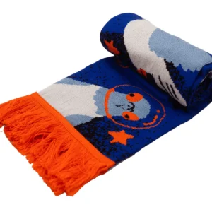 A rolled blue and orange woven “Pigeon - Organic” scarf with orange fringes, featuring a playful illustrative design of a stylised owl wearing glasses surrounded by stars. Gate21.ee