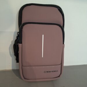 An &ldquo;Astoria - Phone Pocket - Old purple&rdquo; zippered pouch with two compartments, featuring convenient New Rebels phone pockets, a visible NEW-REBELS logo, and a thin vertical white stripe on the front, stands upright against a white wall on a grey surface. Gate21.ee