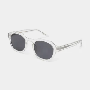 Zan - Crystal sunglasses by A. Kjærbede, featuring clear frames and round, dark lenses, displayed at a three-quarter angle on a plain white background. The arms and bridge are crafted from transparent material. Gate21.ee