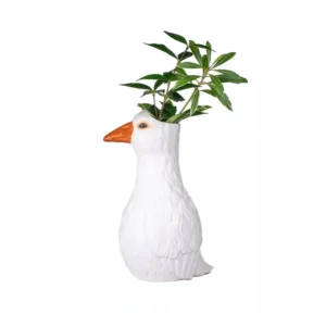 Goose - Vase featuring a white goose with an orange beak, designed to hold a green leafy plant that appears to grow from the top of the goose’s head, set against a white background. Gate21.ee