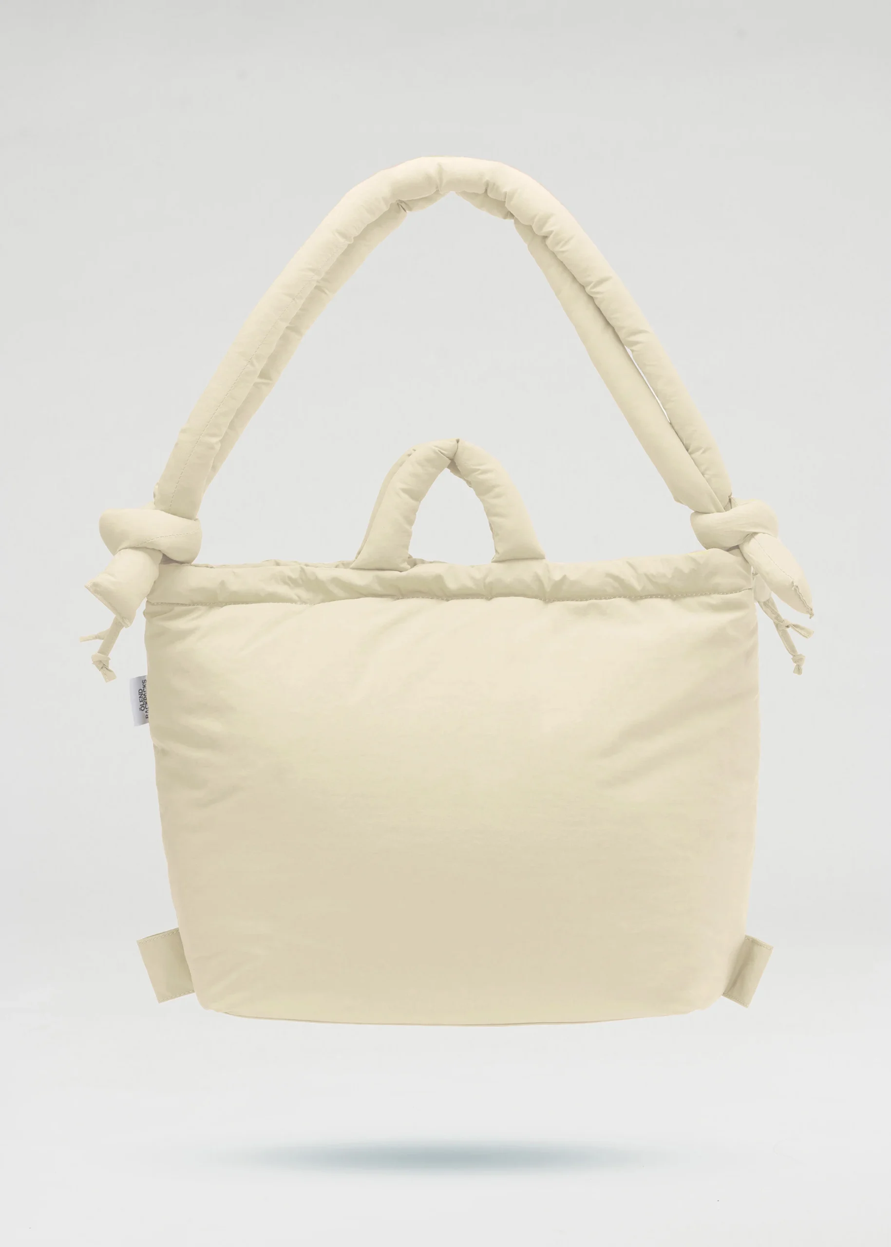 A butter yellow, padded ÖLEND Ona Soft Bag with two short handles and two longer, knotted shoulder straps, displayed against a plain white background. The bag has a soft, quilted appearance. Gate21.ee