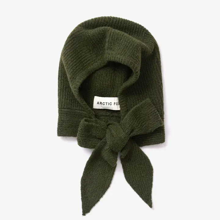 Introducing The Bonnet - Forest Green - Recycled: a dark green knitted hood with a wide front opening and a large bow at the bottom, featuring an inner label that reads “ARCTIC FOX.” Inspired by the cosy warmth of Arctic Fox Reykjavik hand warmers, this stylish accessory is perfect for chilly days. Gate21.ee