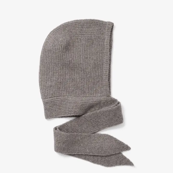 A soft, textured bonnet in earthy grey, crafted from recycled materials, features a knitted hood with two long, wide ties at the base—designed to be wrapped or tied under the chin—evoking the cosy warmth of Arctic Fox Reykjavik hand warmers. Gate21.ee