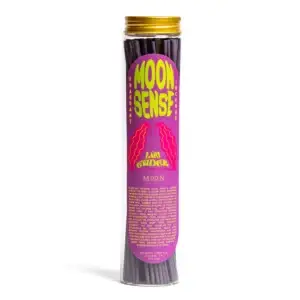A clear cylindrical jar with a gold lid contains purple incense sticks. The label prominently displays “Moon Sense: Lavendar” in large text, with “Lava Guder” and “Moon” below, followed by product details in small print at the bottom—making it a unique addition to the Wick & Vessel home fragrance collection. Gate21.ee